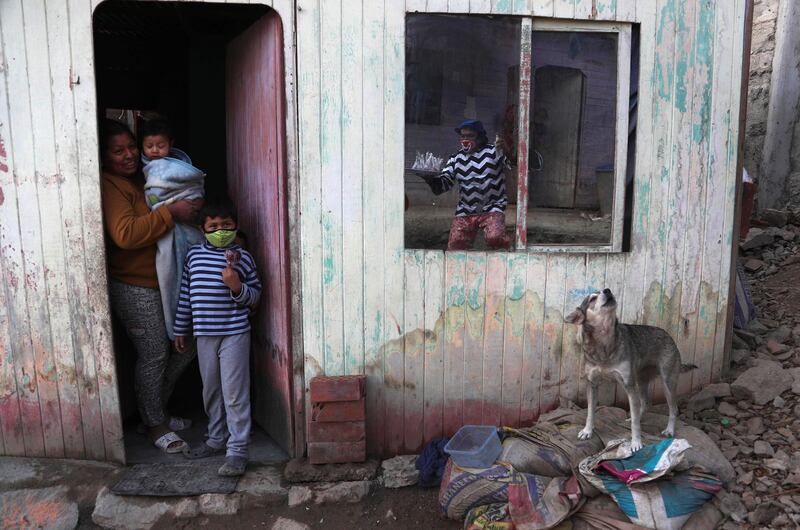 Circus clown Jhona Zapata, whose performance name is "Jijolin," is reflected in the window of a home as he offers caramelized apples for sale, while circuses are closed during the lockdown to curb the spread of COVID-19 in a poor neighborhood on the outskirts of Lima, Peru. Zapata, 35, is selling circus food to help his family survive the economic shutdown. AP Photo