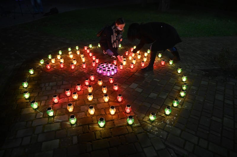 Girls wearing face masks place candles among others forming a radioactivity sign at the monument to Chernobyl victims in Slavutich, the city where the power station's personnel lived, some 50 kilometres from the accident site, on April 26, 2020.  AFP