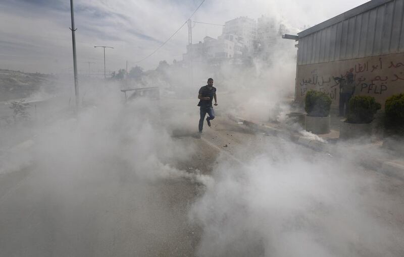 A Palestinian protester runs from tear gas fired by Israeli troops during clashes near Israel’s Ofer Prison, near the West Bank city of Ramallah. Mohamad Torokman / Reuters