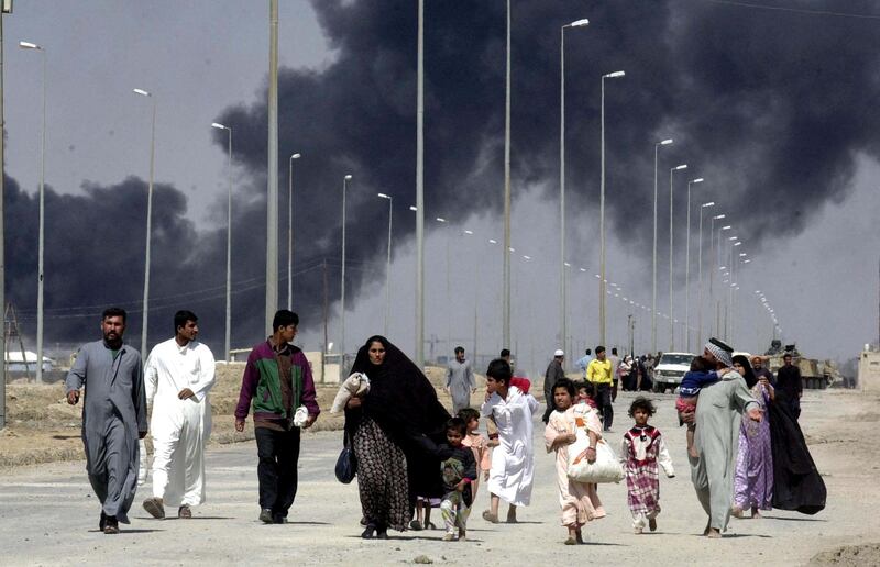 Residents flee the burning town of Basra in southern Iraq on March 28, 2003. British soldiers said the fleeing refugees had described a city still in the grip of an Iraqi military that had hidden large amounts of artillery tanks in civilian and commercial areas. AFP