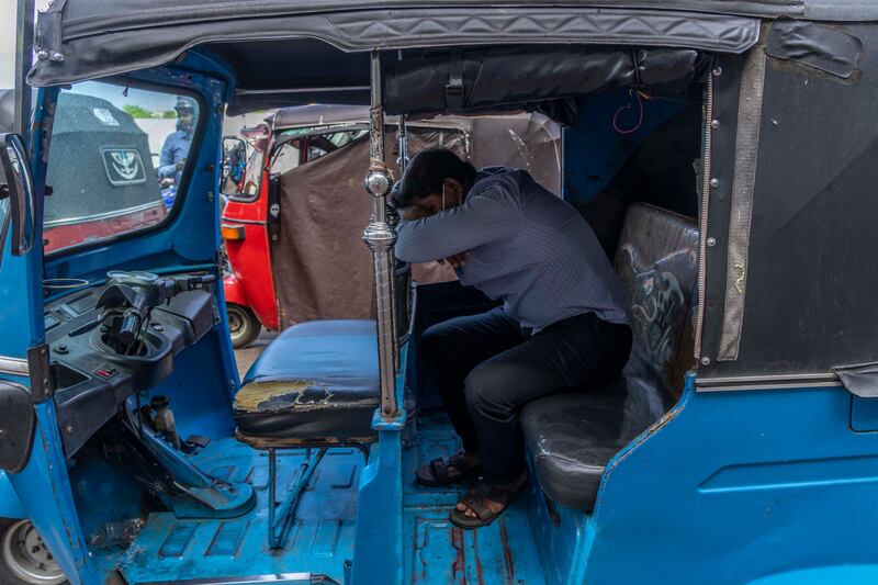 A driver of an autorickshaw sleeps inside his vehicle while waiting in a queue to buy petrol at a fuel station in Colombo. AP