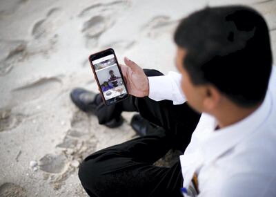 DUBAI, UNITED ARAB EMIRATES. 15 OCTOBER 2019. 
Syed Mohammed looks at a photo of his children in Pakistan. Mohammed has been in the UAE since he was  three years old. He now works as a Careem driver. On his time off, he enjoys a swim and a walk at the beaches here.

(Photo: Reem Mohammed/The National)

Reporter: ANNA ZACHARIAS
Section: NA