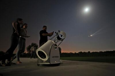 People stand to watch a partial lunar eclipse through a telescope at the Al Thuraya Astronomy Center in Dubai, United Arab Emirates, Tuesday, July 16, 2019. (AP Photo/Kamran Jebreili)