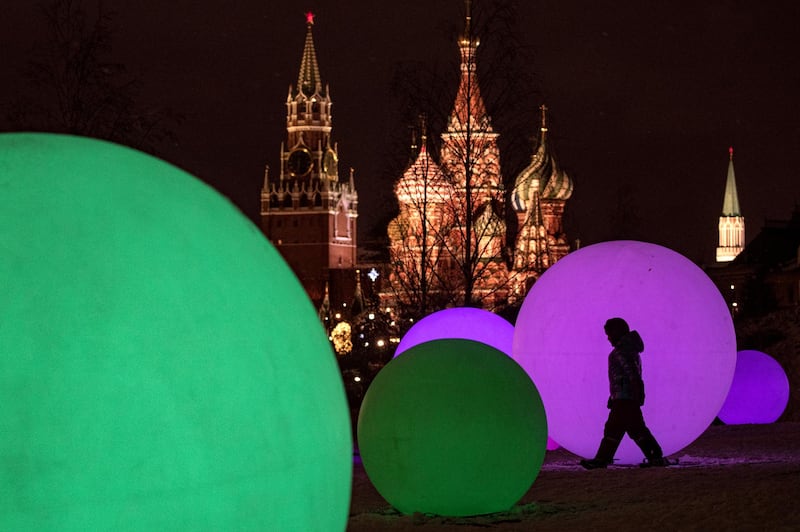 A boy is silhouetted against light spheres, part of decorations for the New Year and Christmas holidays, in front of  the Spasskaya Tower and St. Basil's Cathedral in Moscow, Russia. EPA