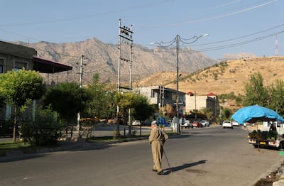 Sheikh Tahir Mohammad Hashim crosses the street in the town of Deraluk, with the mountains in the background. Chris Whiteoak / The National
