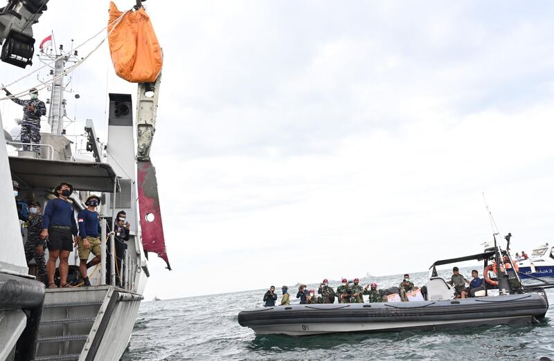 Navy sailors recover a piece of wreckage (bottom centre, in red) during recovery operations near Lancang Island. AFP