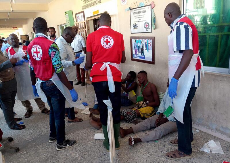 EDITORS NOTE: Graphic content / Red Cross officials attend to victims of a triple suicide bombing, which occured outside a hall in Konduga, 38 kilometres (24 miles) from the Borno state capital Maiduguri, northeast Nigeria, on June 17, 2019.

 Thirty people were killed late on June 16 in a triple suicide bombing in northeast Nigeria, emergency services reported, in an attack bearing the hallmarks of the Boko Haram jihadist group. Three bombers detonated their explosives outside a hall in Konduga, 38 kilometres (24 miles) from the Borno state capital Maiduguri, where football fans were watching a match on TV. / AFP / Audu Ali MARTE
