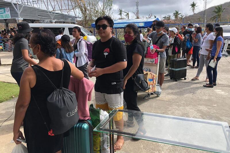 People queue up to board a humanitarian flight out of Siargao airport in Del Carmen, days after Typhoon Rai hit. AFP