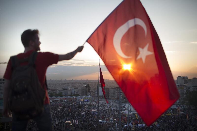 A protestor waves the Turkish flag from a roof top at Taksim Square to protest the actions of president Recep Tayyip Erdogan. Photo: Uriel Sinai / Getty Images