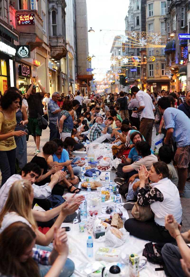 Turkish anti goverment protesters gather as they break their first day of fasting for the Muslim holy month of Ramadan on Istiklal street, the main shopping corridor, on July 9, 2013 in Istanbul. During the month devout Muslims must abstain from food, drink and sex from dawn until sunset, when they break the fast with the meal known as Iftar. AFP PHOTO/BULENT KILIC
 *** Local Caption ***  522286-01-08.jpg