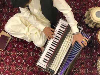 Afghan harmonium player Shafiq Baksh tunes his instrument before a performance. Hikmat Noori for The National