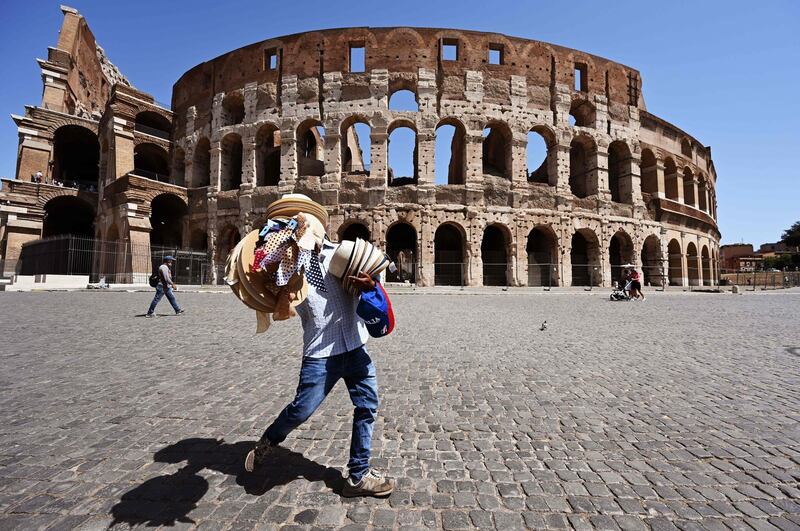 A street seller carries straw hats and caps outside the Colosseum monument in Rome.  AFP