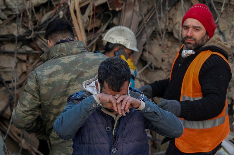 The brother of a survivor Gokhan Ugurlu, 35, who was pulled out of the rubble in Hatay, Turkey, reacts as a rescuer looks on. Reuters