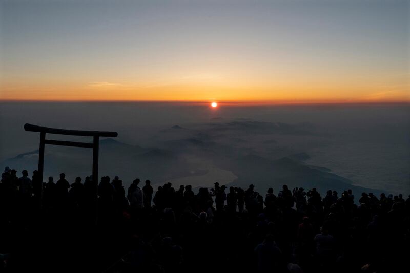 People gather around a torii gate as they watch the sunrise from the summit of Mount Fuji.  AP