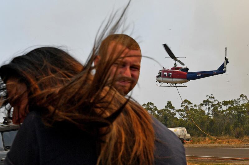 Commuters are seen as a Rural Fire Service (RFS) helicopter lands on the Princes Highway near the town of Sussex Inlet. Getty