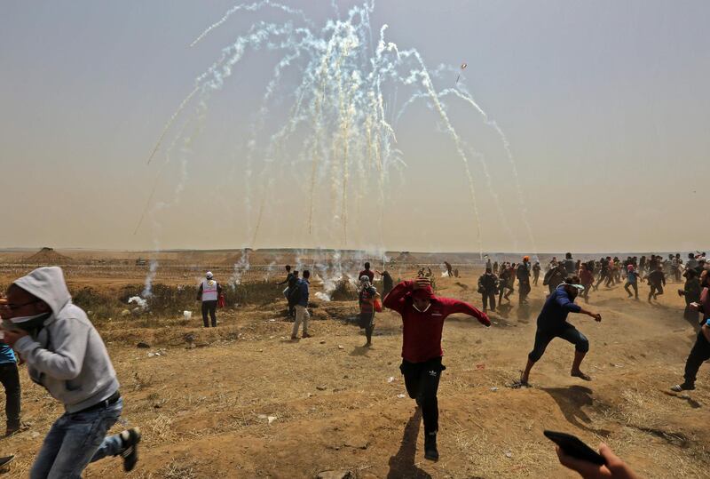 Palestinians take cover from tear gas smoke during clashes with Israeli security forces near the border fence with Israel, east of Gaza City in the central Gaza Strip on April 13. Mahmud Hams / AFP Photo