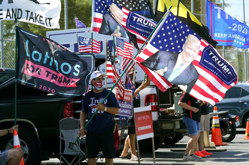 Supporters of President Donald Trump wave flags outside an early voting station at the John F Kennedy Library in Hialeah, Florida. AP Photo