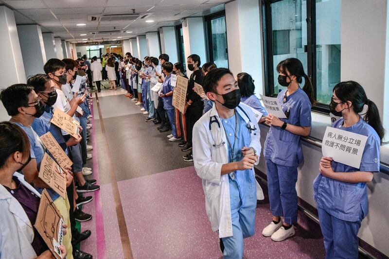 Medical staff hold posters as they form a human chain to express solidarity with anti-extradition bill protesters during their lunch break at the Queen Mary Hospital in Hong Kong.   AFP