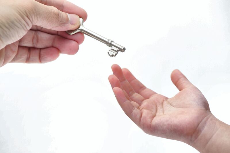 concept image of a older hand handing key to the younger next generation. 