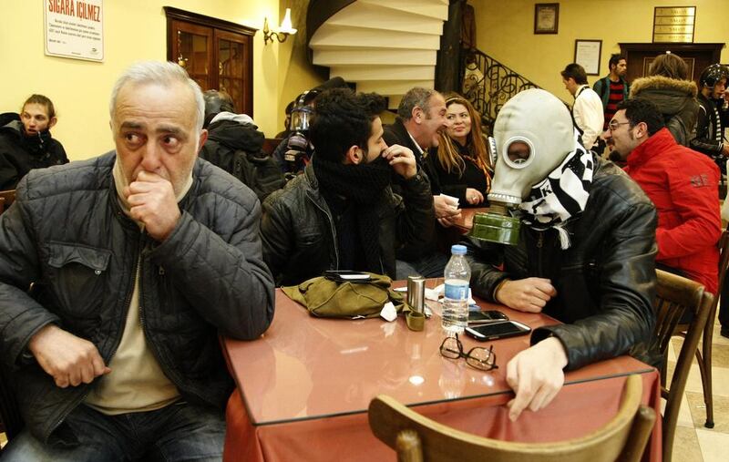 A protester wearing a gas mask sits in an Istanbul restaurant on February 22, 2014, as protesters clash with riot police during an anti-government protest against new internet restrictions. The new law blocks websites and lets government access users’ browsing history, which protesters say will lead to greater censorship in Turkey. Ulas Yunus Tosun / EPA