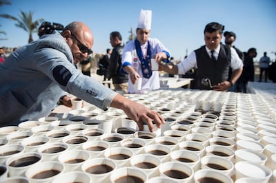 epa08092556 Helpers arrange cups with black coffee and milk coffee to create a mosaic depicting the ancient Egyptian pharaoh Tutankhamun's death mask outside the Grand Egyptian Museum (GEM), in Giza, Greater Cairo, Egypt, 28 December 2019. Media reports state that Guinness World Records organized the event to celebrate Egypt for 'breaking the world record with a picture of King Tutankhamun's mask' by using a total of 7,260 cups of coffee. The mosaic was meant as a 'symbol of love and greeting' according to an Egyptian Ministry of Tourism and Antiques statement. The museum is scheduled to present its full Tutankhamun collection by the end of 2020.  EPA/MOHAMED HOSSAM