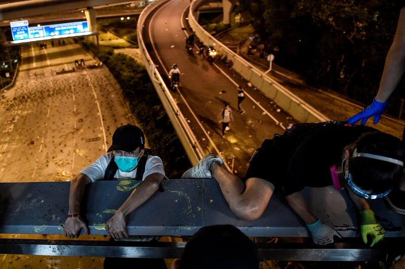 Protesters take a rope down from a bridge to a highway, to escape from Hong Kong Polytechnic University campus and from police, in Hung Hom district in Hong Kong.  AFP