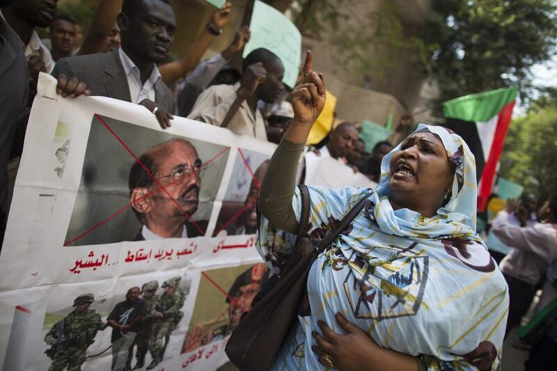 A Sudanese woman stands beside a banner that reads: "The people want to bring down Al Bashir" during a protest against the government's reaction to fuel price demonstrations outside the Sudanese embassy in Cairo. Hassan Ammar / AP