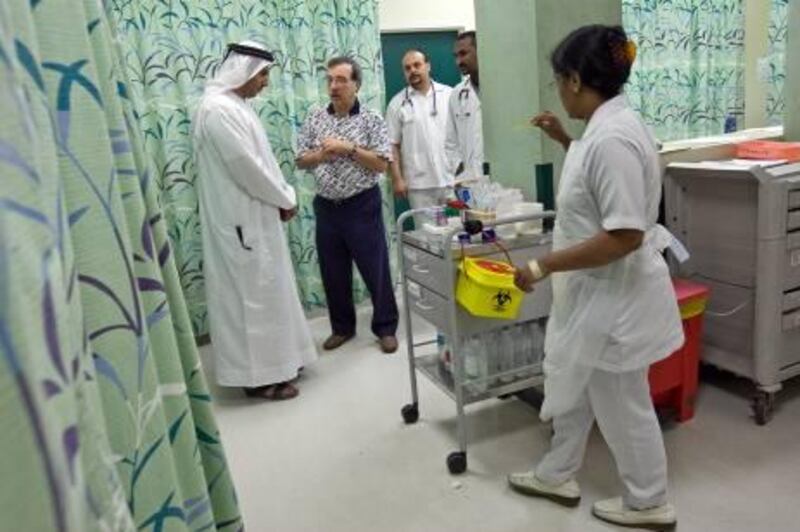United Arab Emirates -Ajman- May 14, 2009:

NEWS: Doctors and nurses consult one another  while tending to patients in the emergency centre of Sheikh Khalifa Hospital in Ajman on Thursday evening, May 14, 2009. (Desk, I do not know who the Emirate is. He stepped into the frame and then disappeared from the room. All others, left to right, are Dr. Ismail Al Baghdadi, in polo shirt, nurse Ahmed Grira (cq-al), Dr. Sayed Abbas (cq-al) and nurse Nancy Samuel, walking. Amy Leang/The National
 *** Local Caption ***  amy_051409_hospital_03.jpg