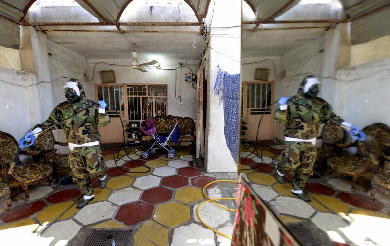 Members of the Iraqi civil defence disinfect a home in Najaf linked to a recent confirmed case of coronavirus.  AFP