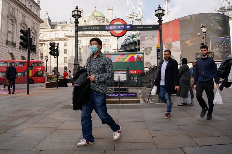 A man wears a face mask as he walks in Piccadilly Circus, in London.  The UK has the highest rate of infections in Europe, with new cases averaging 43,000 a day over the past week. AP Photo