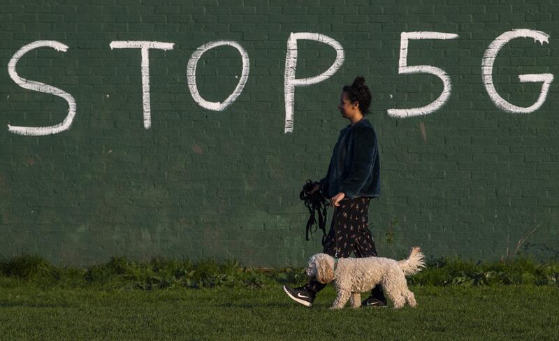 LONDON, UNITED KINGDOM - APRIL 10: A woman walks her dog in-front of graffiti saying 'Stop 5G' on April 10, 2020 in London, England. Public Easter events have been cancelled across the country, with the government urging the public to respect lockdown measures by celebrating the holiday in their homes. Over 1.5 million people across the world have been infected with the COVID-19 coronavirus, with over 7,000 fatalities recorded in the United Kingdom.   (Photo by Justin Setterfield/Getty Images)