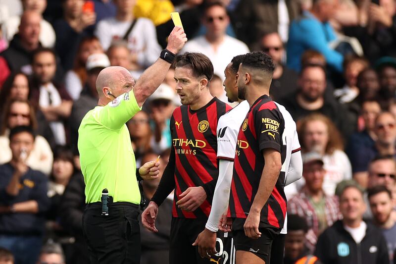 City's Jack Grealish and Kenny Tete of Fulham are both shown yellow cards by referee Simon Hooper. Getty