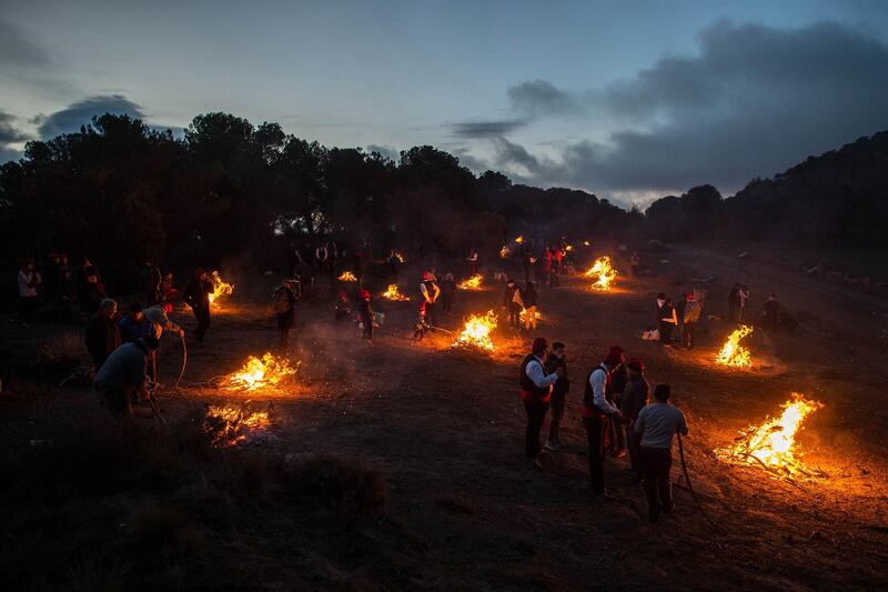 'Galejadors' light bonfires in the forest during 'la Festa del Pi' (The Festival of the Pine) in Centelles, Spain. Early in the morning men and women born in Centelles, who are named 'Galejadors' wear their traditional costume with the Catalan red hat known as 'Barretina' and carry their shooting muskets as they walk into the forest to chop down a pine tree, load it on an ox cart and take it to the church in the village. The pine tree is decorated with five bouquets of apples and wafers and hung inside a church until January 6. The tradition has been documented since 1751 and it is believed its origins are related to the trees and the pagan worship of fertilisation related to the winter solstice.  David Ramos / Getty Images