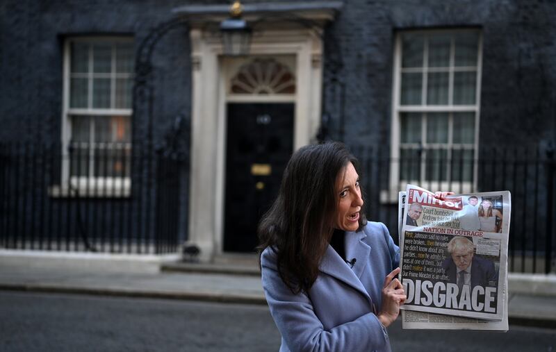 A member of the international media holds up a newspaper front page outside 10 Downing Street as Boris Johnson's polling rating slumps after Partygate. EPA