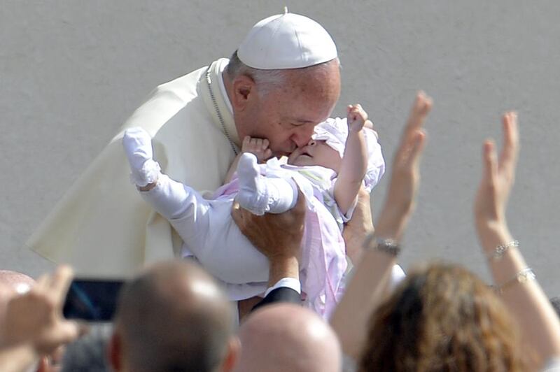 Pope Francis kisses a baby as he arrives for his general audience at St Peter’s Square at the Vatican. Andreas Solaro / AFP