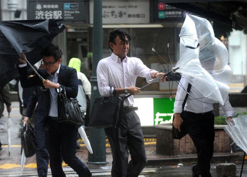 Japanese businessmen walk against strong winds and rain in Tokyo. Yoshikazu Tsuno / AFP Photo