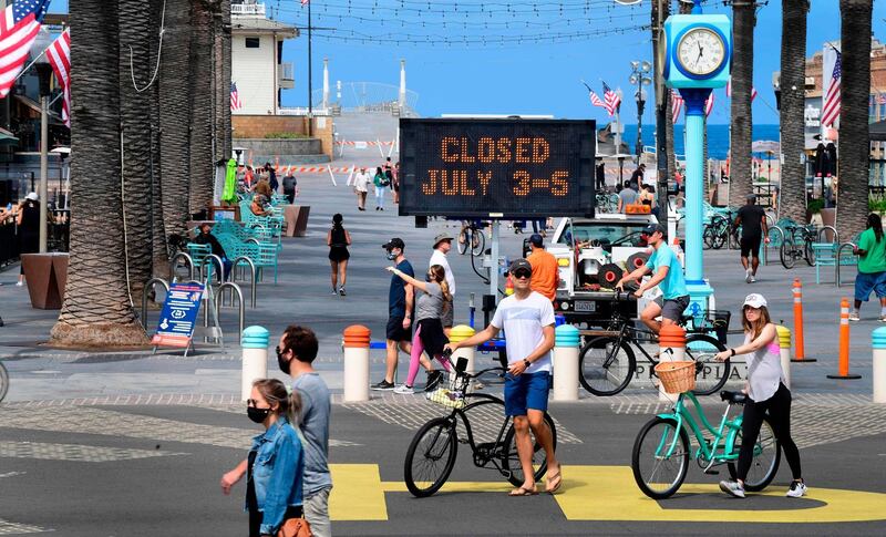 People make their way past the street leading to the pier at Hermosa Beach in Hermosa Beach, California on July 3, 2020.  Los Angeles County beaches will be closed for the Fourth of July weekend due to the spike in COVID-19, novel coronavirus, cases as officials fear increased hospitalizations and an overwhelmed healthcare system in coming weeks. / AFP / Frederic J. BROWN
