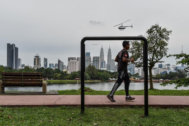 A man jogs at a park as while Malaysia's iconic landmark Petronas Twin Towers (center-R) dominate the skyline of Kuala Lumpur on June 26, 2018. (Photo by Mohd RASFAN / AFP)