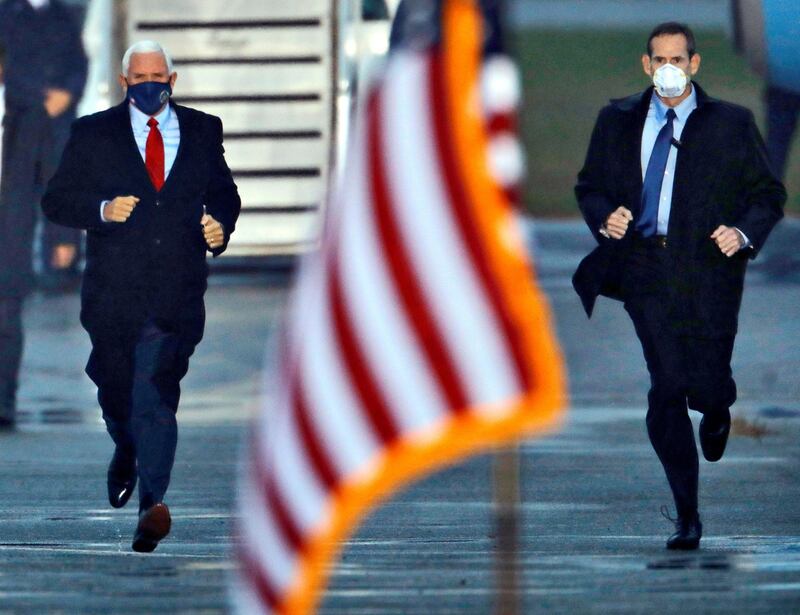 U.S. Vice President Mike Pence runs from his plane to the podium while a secret service agent keeps pace with him as they arrive at a rally in Kinston, North Carolina, U.S. REUTERS