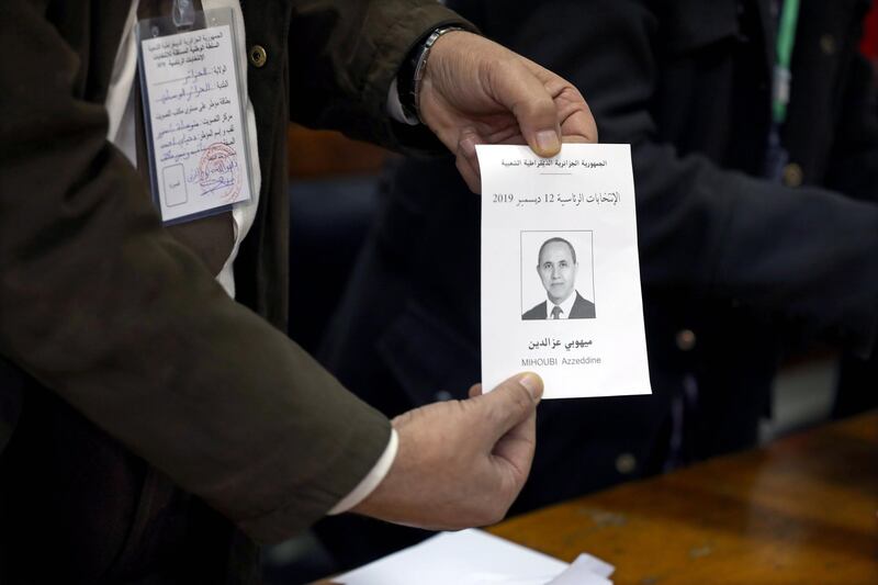 An election official holds a ballot paper showing presidential candidate Azzedine Mihoubi during vote counting at a polling station in Algiers, Algeria. EPA
