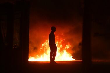 A protester stands near a burning car as police were attacked on the outskirts of Belfast, Northern Ireland. Getty