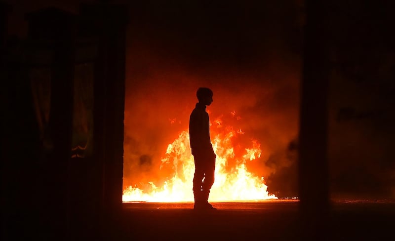 BELFAST, NORTHERN IRELAND - APRIL 03: A protestor stands near a burning car as police attend the scene at Cloughfern as Loyalist protestors hijack and burn vehicles on April 3, 2021 in Belfast, Northern Ireland. Loyalist unrest and disorder in the province continues as a result of the implementation of the so called Irish sea border. (Photo by Charles McQuillan/Getty Images) ***BESTPIX***