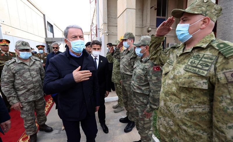 Turkey's Defense Minister Hulusi Akar, centre, and Turkey's Chief of Staff Gen. Yasar Guler, left, greet Libyan and Turkish commanders commanders, in Tripoli, Libya, Saturday, Dec, 26, 2020. Akar arrived in Tripoli Saturday, where they were meeting with their allies, Libya's UN-backed Government of National Accord, according to the Turkish Defence Ministry.(Turkish Defense Ministry via AP, Pool )