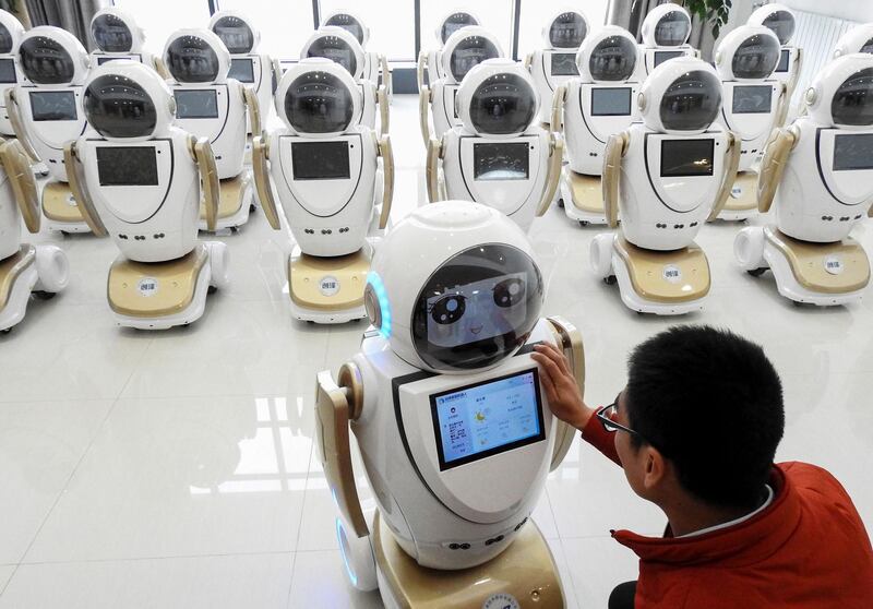 An employee checks robots used for customer services at a factory in Lianyungang in China's eastern Jiangsu province. AFP