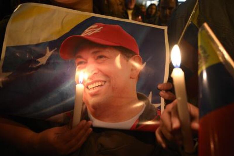 A supporter of Venezuelan President Hugo Chavez holds a poster of him and a candle outside the Venezuelan embassy in Quito after knowing of his death. AFP Photo / Rodrigo Buendia