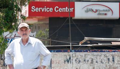 A man stands across Syria's largest mobile operator Syriatel, owned by businessman Rami Makhlouf, in the Syrian capital Damascus on May 11, 2020. Syria's top tycoon publicly airing his grievances has revealed a power struggle within the ruling family as it tries to cement its power after nine years of war, analysts say. After years of staying out of the limelight, business magnate Rami Makhlouf this month in two videos on Facebook laid bare his struggles with the regime headed by his first cousin President Bashar al-Assad, in what analysts say is a desperate last stand. / AFP / STR
