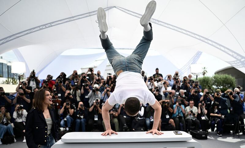 Actor Tom Mercier performs acrobatics as actress Billie Blain watches on at a photocall for the film Le Regne Animal at the Cannes Film Festival. AFP