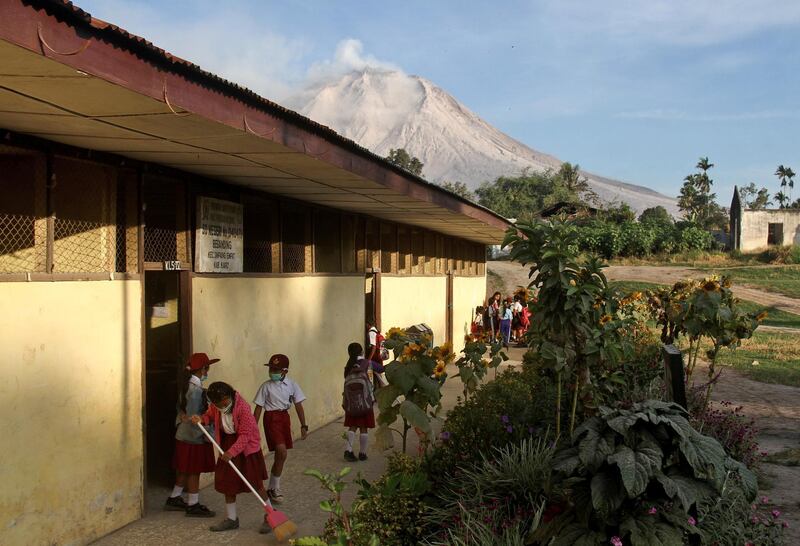 Students prepare before the start of their class as Mount Sinabung is seen in the background, at an elementary school in Beganding, North Sumatra. Ahmad Putra / AP Photo
