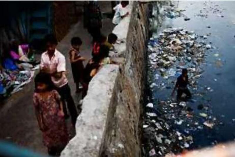 A boy sifts through garbage in an open sewer in the Dharavi slum on Thursday, October 30, 2008. The old slums, one of the largest in Asia with close to one million residents would be converted in to multi story apartment buildings and commercial areas if Mukesh Metha's Slum Redevelopment Plan is successful.  *** Local Caption ***  NATIONAL_Dharavi_Slumrelocate_10-29-08_0903.JPG