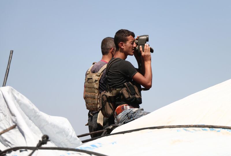 A Syrian rebel looks with binoculars during battles with pro-government fighters in western Daraa province on July 10, 2018. 
 A suicide car bombing today killed 14 newly reconciled fighters from pro-government and rebel ranks in an attack on a south Syrian village claimed by the Islamic State group. / AFP / Ahmad al-Msalam
